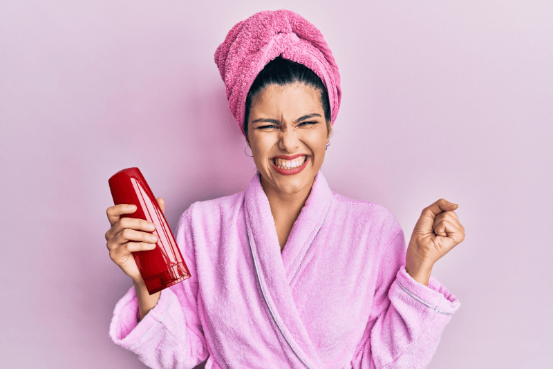 Mujer con bata y toalla rosadas que sostiene un envase rojo